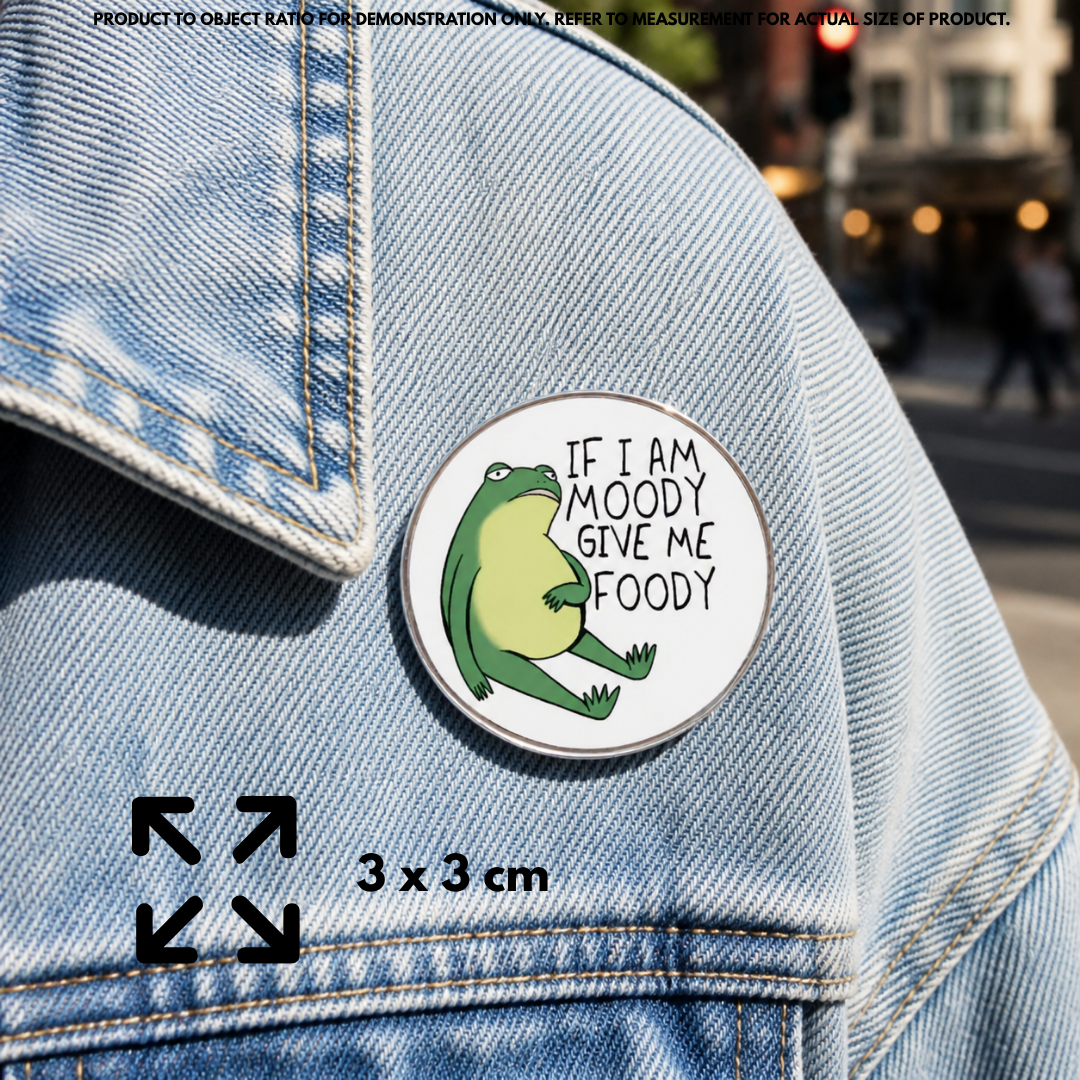Person holding "If Moody Give Foody" enamel pin showing 3×3cm size