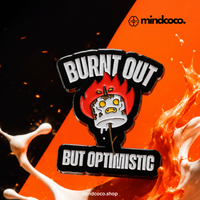 "Burnt Out But Optimistic" enamel pin – lifestyle flat lay, neurodivergent and mental health humour