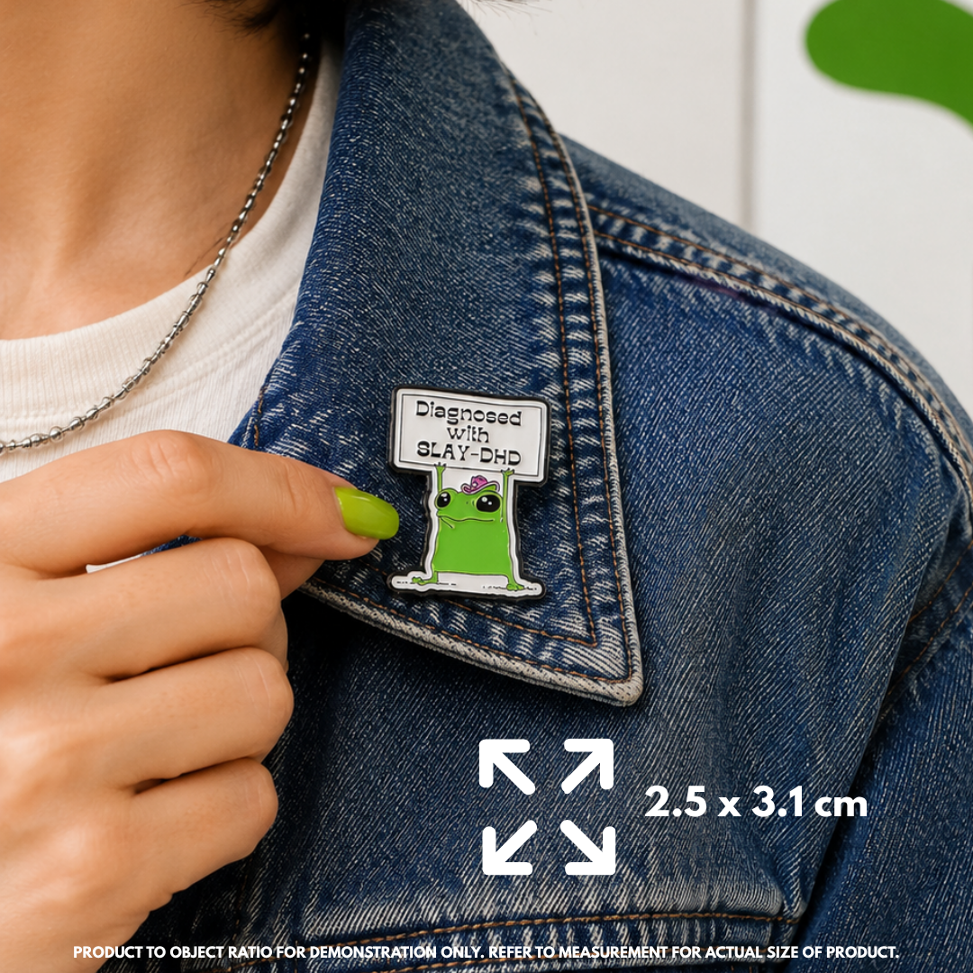 Person holding "SlayDHD" enamel pin showing 3×3cm size