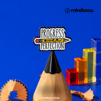"Progress Over Perfection" enamel pin – lifestyle flat lay, neurodivergent and mental health humour