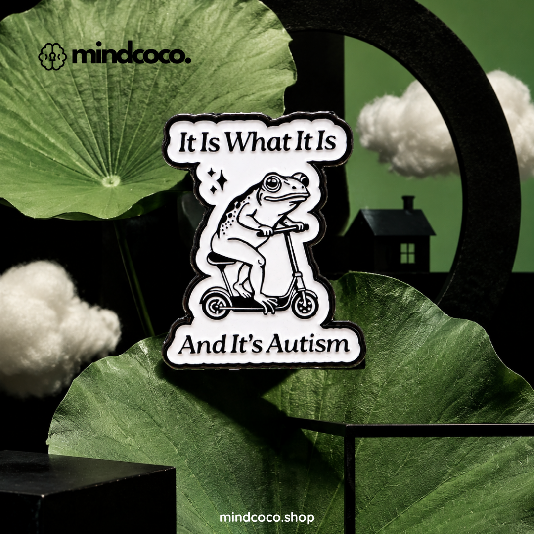 "It is What It Is" enamel pin – lifestyle flat lay, neurodivergent and mental health humour