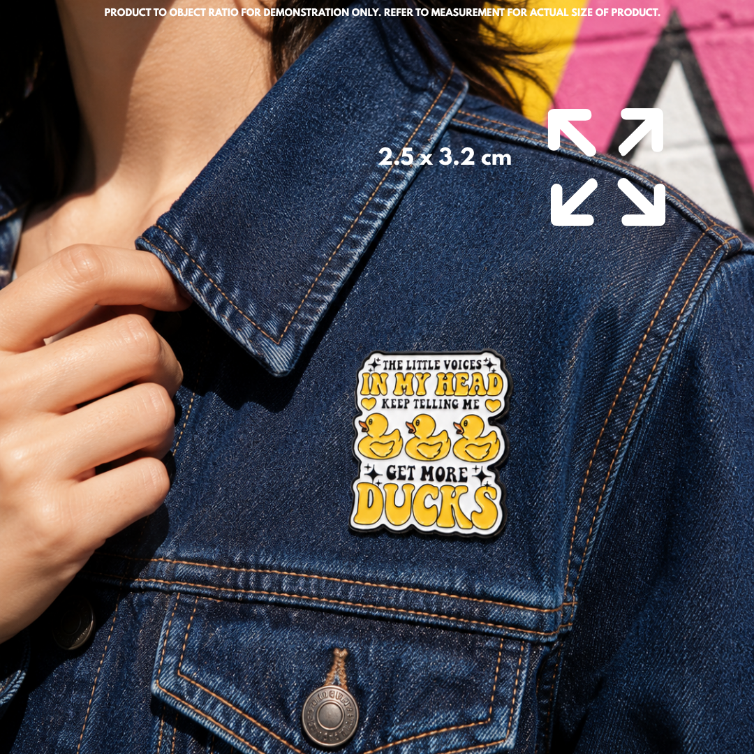 Person holding "Get More DUCKS" enamel pin showing 3×3cm size