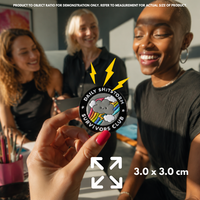 Person holding "Daily Shitstorm Survivors Club" enamel pin showing 3×3cm size