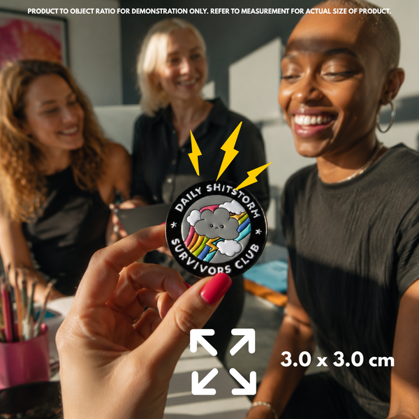 Person holding "Daily Shitstorm Survivors Club" enamel pin showing 3×3cm size