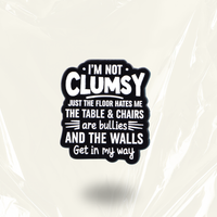 MindCoco "I'm Not Clumsy Just the Floor Hates Me" Pin: A high-contrast black and white text-only enamel badge. This long-form, painfully relatable accessory validates spatial awareness struggles for ADHD and autistic individuals with a touch of defensive humor.