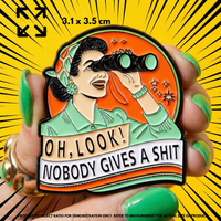 Person holding "OH, LOOK! NOBODY GIVES A SHIT" enamel pin showing 3×3cm size