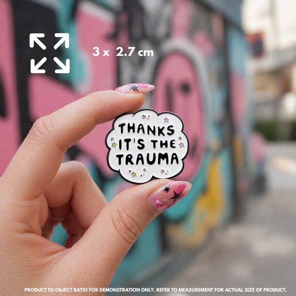 Person holding "Thanks It's The Trauma" enamel pin showing 3×3cm size